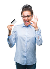 Wall Mural - Young african american girl holding credit card over isolated background doing ok sign with fingers, excellent symbol