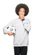 © Krakenimages.com - Young african american man with afro hair holding soccer football ball cover mouth with hand shocked with shame for mistake, expression of fear, scared in silence, secret concept
