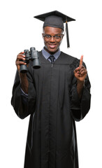 Wall Mural - Young graduated african american man looking for a job using binoculars surprised with an idea or question pointing finger with happy face, number one