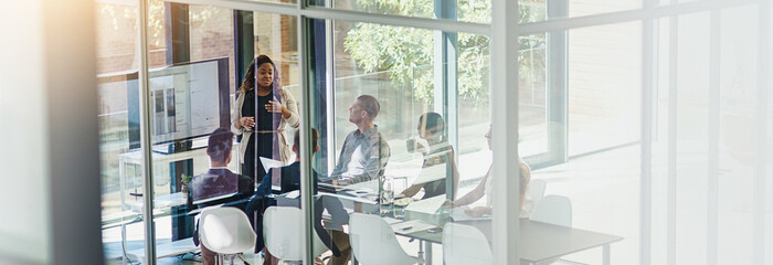Poster - Woman, screen and presentation with group in boardroom, charts and review for stats at startup. Speaker, monitor and graphs with brand communication, above and discussion with team in modern office