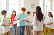 © Studio Romantic - Teacher conducting a music lesson with students in a school classroom. The group of children participates in singing and learning together, highlighting creative atmosphere of the class.