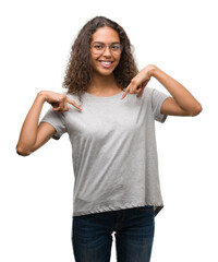 Wall Mural - Beautiful young hispanic woman wearing glasses looking confident with smile on face, pointing oneself with fingers proud and happy.