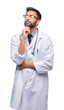 © Krakenimages.com - Adult hispanic doctor man over isolated background with hand on chin thinking about question, pensive expression. Smiling with thoughtful face. Doubt concept.