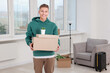 © New Africa - Happy man with moving boxes and houseplant in new apartment. Housewarming party