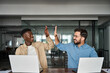 © insta_photos - Two happy diverse young professional male employees team giving high five at work. African and Hispanic business men buddies celebrating good corporate teamwork results, startup success together.