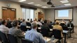 © Samraoy - Business professionals gathered at seminar listening to a presentation in a conference room