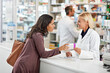 © peopleimages.com - Drugstore, woman and consulting pharmacist by counter for pills side effects, prescription drugs dosage and advice. Friendly, expert and customer service in pharmacy with medication box information