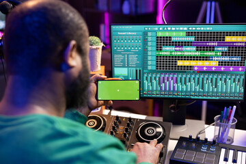 Poster - African american audio technician recording and editing tunes with pc software, looks at mockup chromakey display. Artist singer producing sounds for his new music, home studio.