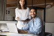 © fizkes - Two joyful Hispanic and Indian teammates working on joint task distracted from workflow, laughing, looking away, enjoy successful teamwork, common task preparation using modern laptop. Apprenticeship