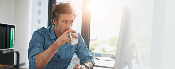 Poster - Computer, coffee and reading with designer man at desk in office for development, planning or research. Banner, mockup and space with mature employee in workplace for online review of information