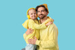 © Pixel-Shot - Cute little girl in headphones hugging her father on blue background. International Hug Day