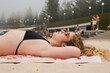 © Érik Glez. - Relaxed Young Woman Wearing Sunglasses is Sunbathing on a Sandy Beach
