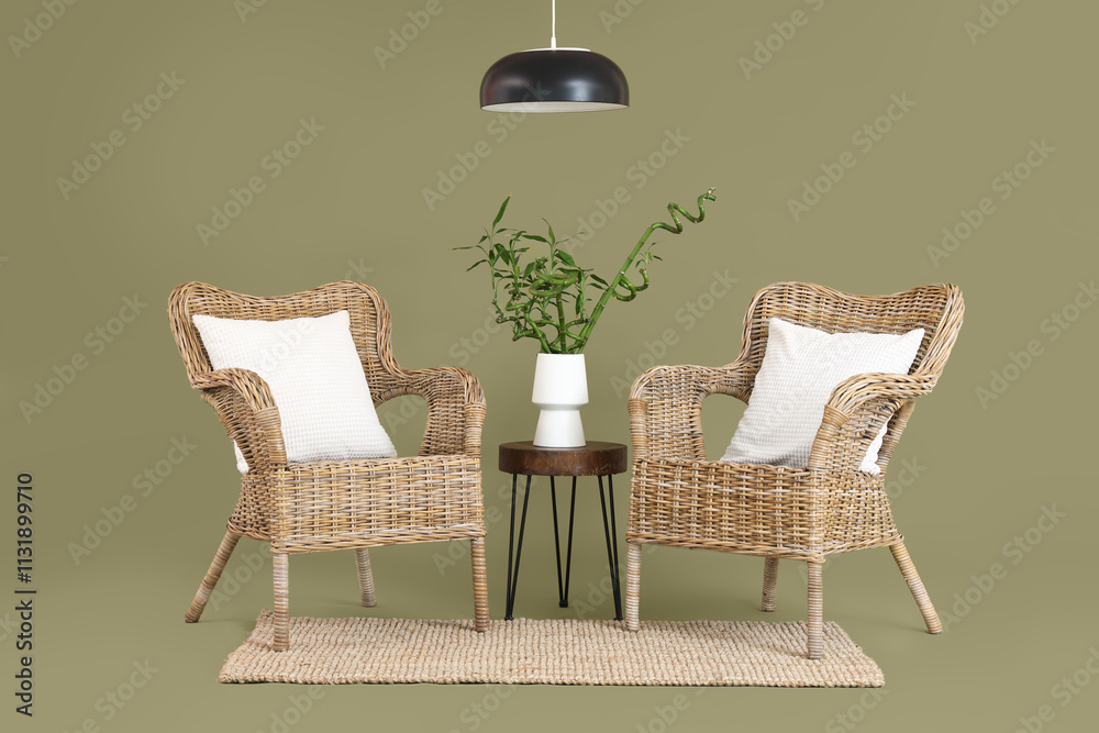 Table with bamboo stems in vase, armchairs and lamp on green background