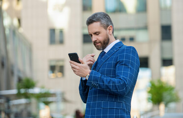 Canvas Print - Hispanic business man with phone at office building. Businessman using phone. Man phone conversation in city. Businessman talking on phone. Businessman in front office. Social network. Online chat