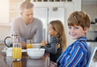 © ReeseFullyOwned/peopleimages.com - Happy child, portrait or breakfast with family in kitchen for morning nutrition, vitamin C or orange juice at home. Father, kid or son with smile for meal, routine or healthy eating together at house
