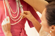 © Brand - Dressmaker arranging pearl necklaces on mannequin with pink dress