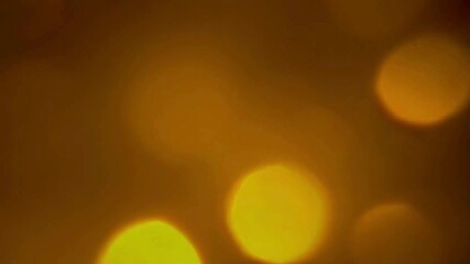 Wall Mural - Golden bokeh lights softly floating and shimmering on a dark, blurred background