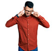 © Krakenimages.com - Young hispanic man with beard wearing business shirt and glasses covering ears with fingers with annoyed expression for the noise of loud music. deaf concept.