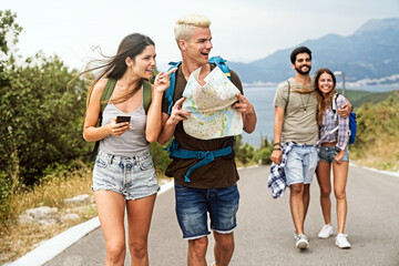 Wall Mural - friendship, travel, vacation, summer and people concept. group of smiling friends with map traveling