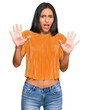 © Krakenimages.com - Young brunette arab woman wearing casual clothes afraid and terrified with fear expression stop gesture with hands, shouting in shock. panic concept.