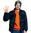 © Krakenimages.com - Young hispanic man with beard wearing snow wear and sky glasses showing and pointing up with fingers number four while smiling confident and happy.