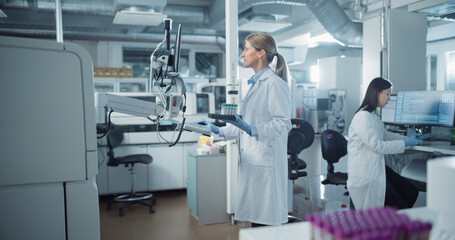 Leinwandbilder - Scientist in White Lab Coat Operates Advanced Testing Equipment in Modern Laboratory. Handling Samples and Analyzing Data on a Computer. Researcher Working with Colleagues in a High-tech Environment