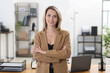 © New Africa - Portrait of happy businesswoman with crossed arms in office
