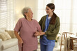 © New Africa - Caregiver assisting senior woman with walking cane indoors. Home health care service