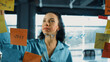 © Summit Art Creations - Portrait of smart professional hispanic businesswoman writes marketing ideas on glass board with colorful sticky notes. Young manager drawing mind map to analysis business plan. Closeup. Manipulator.