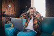 © deagreez - Excited young man in plaid shirt enjoying surprise on laptop while relaxing on sofa in stylish living room