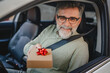 © Miljan Živković - Senior mature man extend hand from the car window with small gift