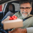 © Miljan Živković - Senior mature man extend hand from the car window with small gift
