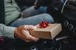 © Miljan Živković - close up males hand hold small gift with red ribbon in the car
