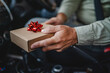 © Miljan Živković - close up males hand hold small gift with red ribbon in the car