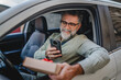 © Miljan Živković - Senior mature man sit in the car and take a photo of gift box