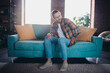 © deagreez - Young man feeling uncomfortable while sitting on a stylish sofa in a bright, trendy living room with natural daylight