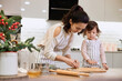 © Rychko Yevhen - Happy family mother and little child daughter cutting cookies of raw gingerbread dough in kitchen. Christmas time