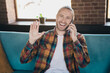 © deagreez - Young man with a happy smile talking on the phone, wearing stylish plaid shirt, sitting comfortably in a bright loft living room