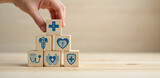 A Health Insurance Concept featuring a hand arranging wooden cubes with healthcare-related icons