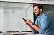 © insta_photos - Smiling professional Hispanic businessman entrepreneur or manager using financial banking apps on cell phone technology at work. Busy happy young business man holding smartphone sitting at office desk