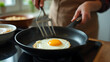 © fotoluigi868 - A woman cooks an egg fried on a black pan during the morning hours as part of her daily food preparation routine._00001_