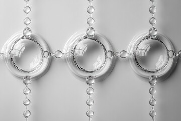 Poster - Three water droplets are positioned in a line, each connected by small droplets, reflecting light and creating intricate patterns on a smooth white background