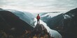 © schiers_images - A person stands atop a rock overlooking a stunning river valley surrounded by mountains. The cloudy sky and serene nature scene reflect a sense of awe, peace, and the beauty of solitude.