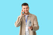 © Pixel-Shot - Male reporter with microphone taking interview on blue background