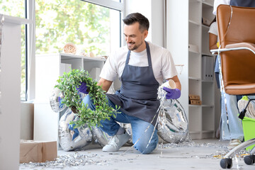 Canvas Print - Male janitor cleaning in office after New Year party