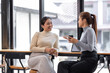 © David - Two asian Female friends drinking coffee and using mobile phones while sitting at cafe