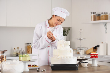 Wall Mural - Female confectioner making cake with cream in kitchen