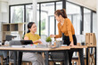 © David - Happy two asian female freelance entrepreneurs reading and planning analyzing the financial report, business plan investment,  on computer while working together in the office.