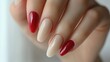 © tengah - A close-up of elegantly manicured nails with a mix of red and nude polish.