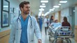 © NOPPHINAN - Smiling doctor walking through hospital hallway with stethoscope, surrounded by busy medical staff and patients, representing healthcare and professionalism.
